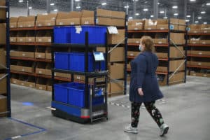 An associate follows Chuck to the next pick location in the Crocs Dayton, Ohio warehouse
