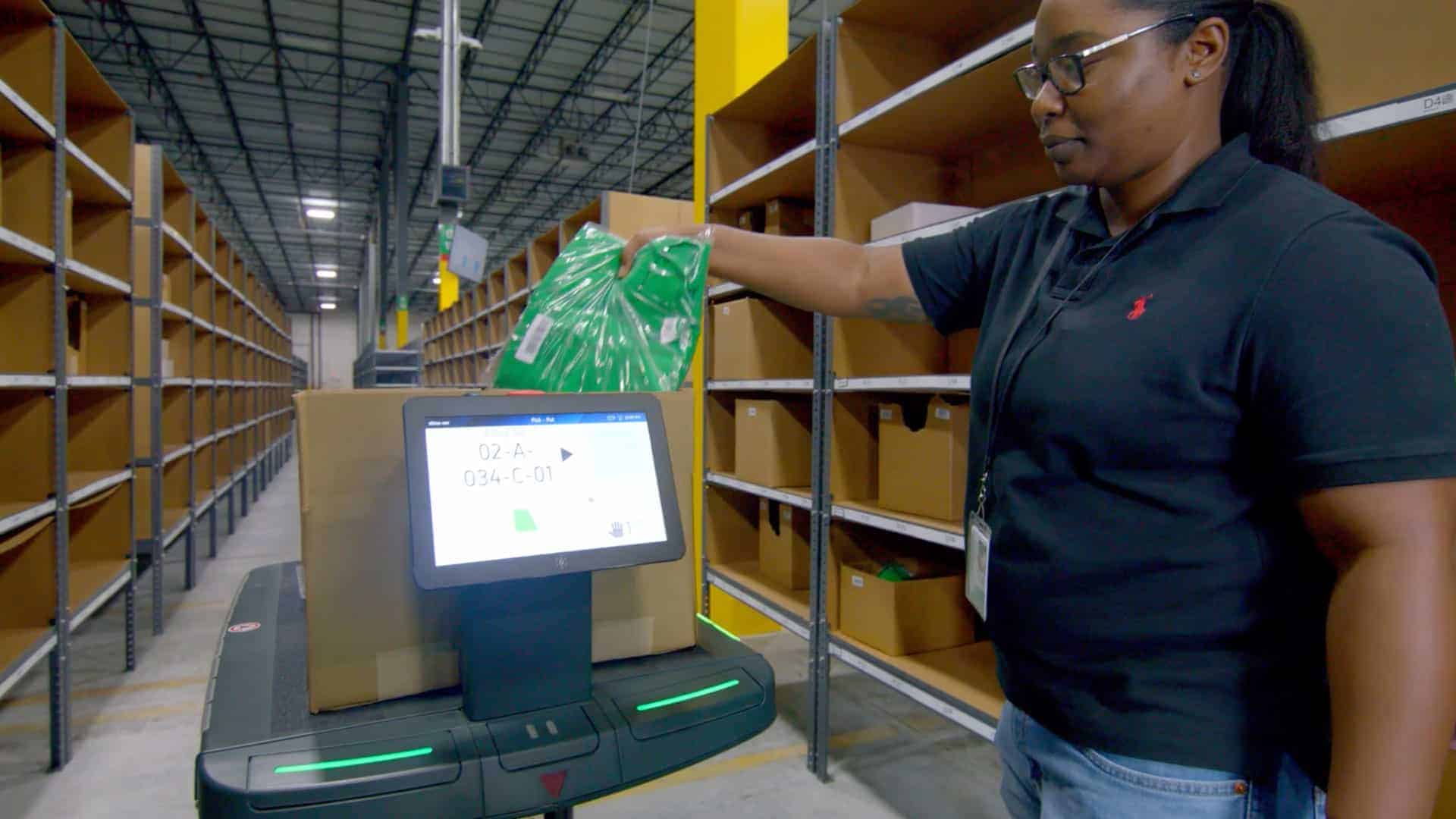 An associate places an item onto a warehouse robot