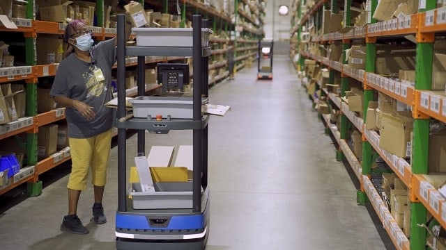 Warehouse associate working with autonomous mobile robot on returns processes